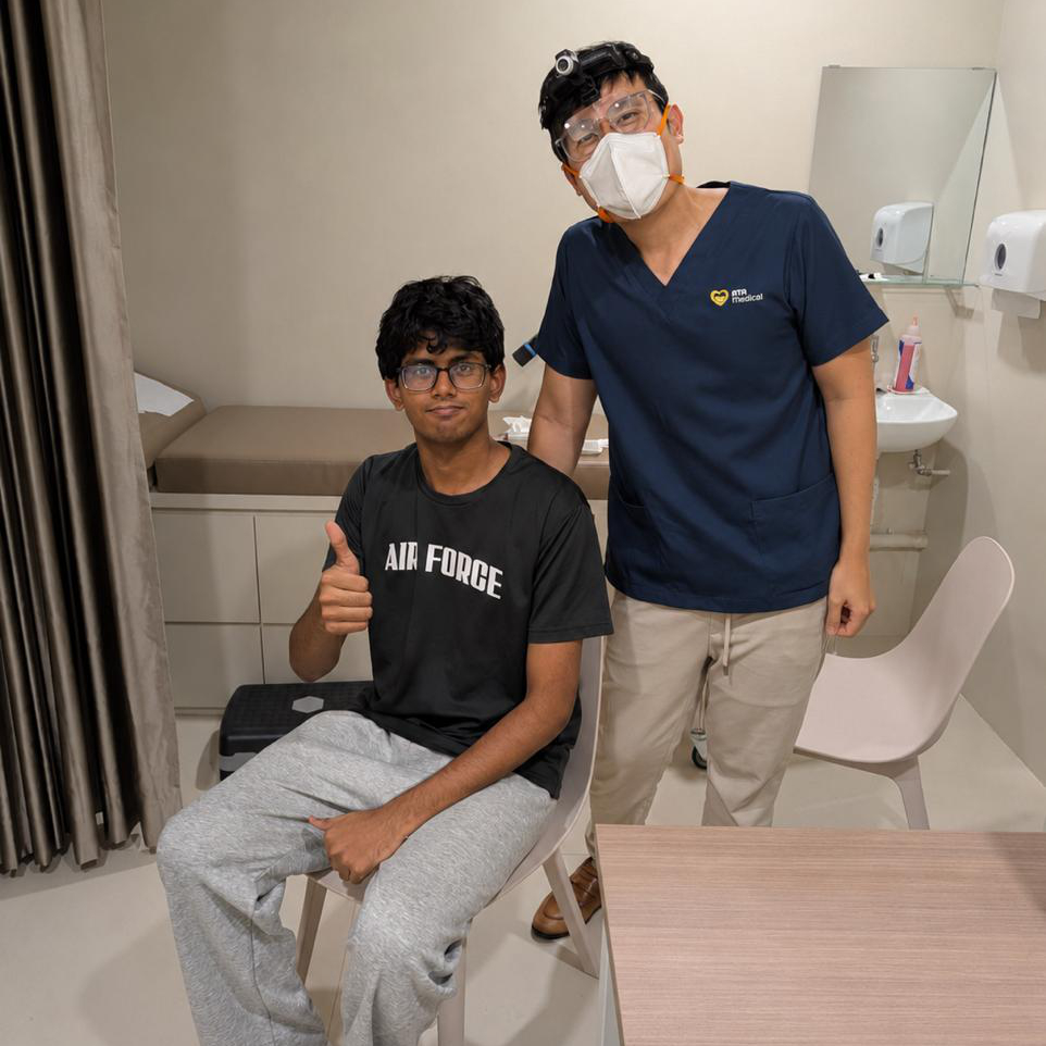 Dr Joel Foo standing beside a male patient giving a thumbs-up after his ear wax removal procedure at the Jurong clinic