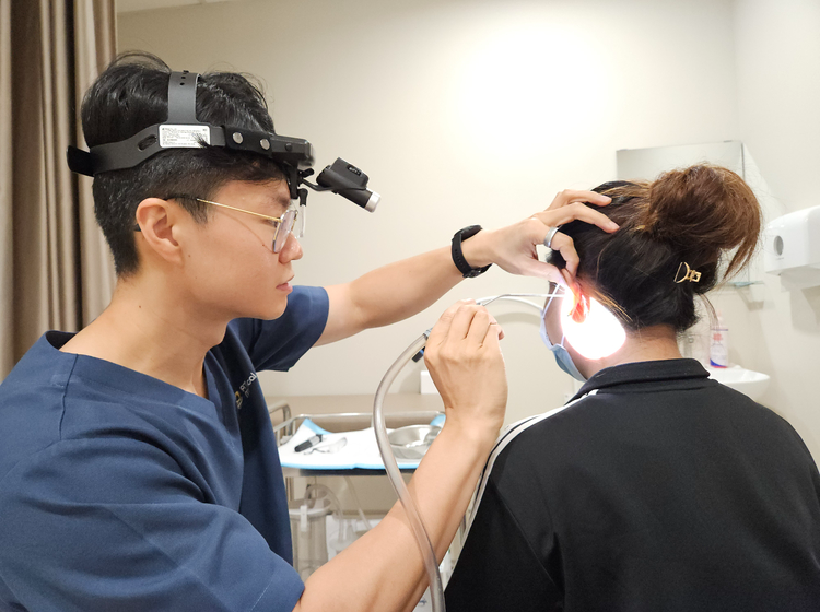 Doctor performing microsuction ear wax removal on a patient
