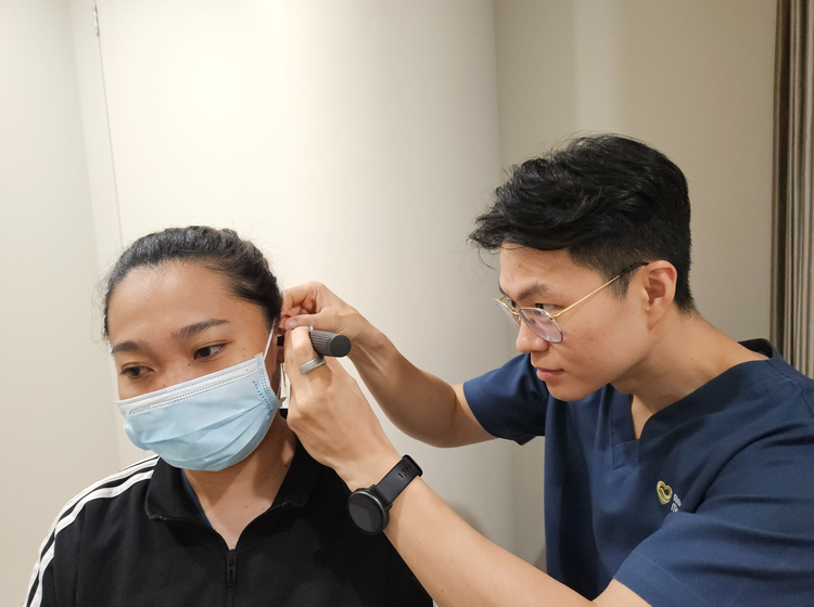 Doctor performing an otoscope examination of a patient's ear canal before ear wax removal